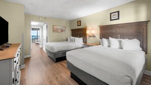 Habitación de hotel con dos camas, televisión, cómoda y vistas al exterior.