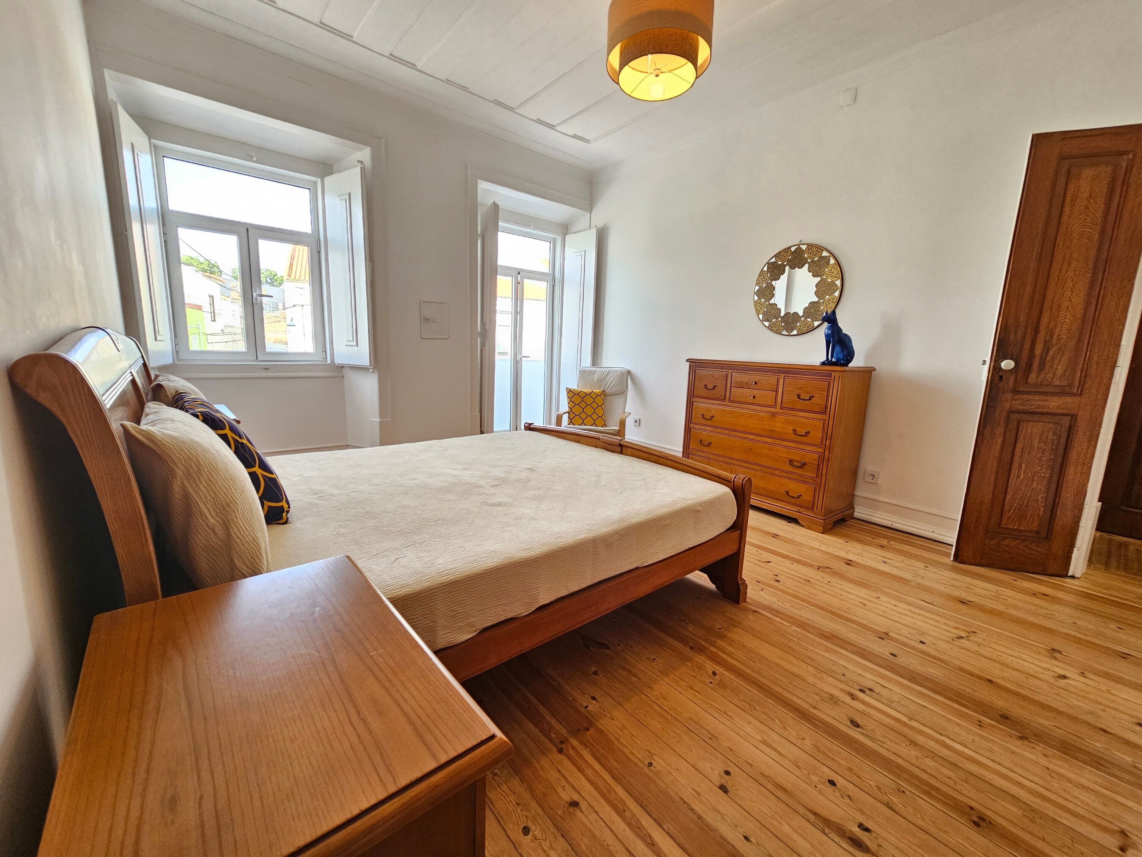 Quarto com cama, cómoda de madeira e penteadeira com espelho.