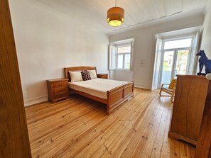 A bedroom with a wooden bed, a nightstand, a dresser, and a window.