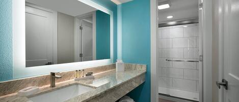 Un baño moderno con un espejo grande, dos lavamanos y una zona de ducha.