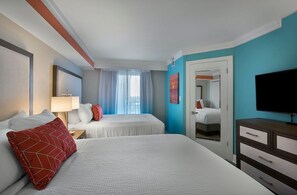A hotel room with two beds, a TV, a desk, and a door leading to another room. - Seaside Gateway in OF 3 BR Condo 16th Floor (Myrtle Beach)