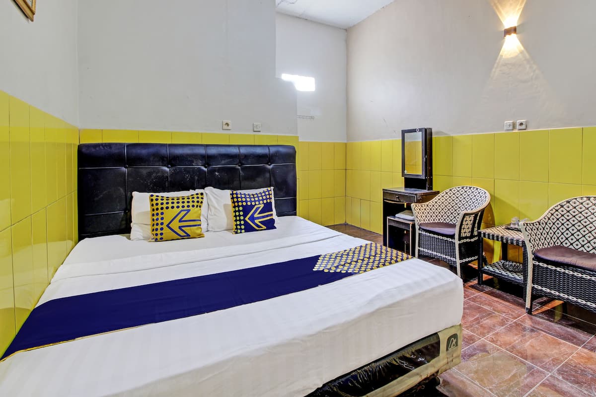 Une chambre d’hôtel avec un lit, un bureau et deux chaises.
