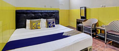 A hotel room with a bed, a desk, and two chairs.