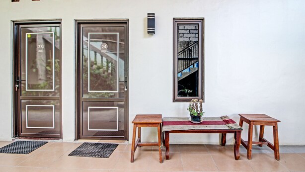 A reception area with two doors, a bench, a small table, and a potted plant. - Hotel O Bagus Jaya Hotel (Ambarawa)