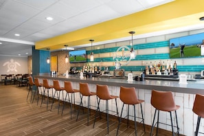 Eine Bar mit Theke, Barhocker und einem Fernseher, der Golf zeigt.