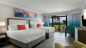 Habitación de hotel con dos camas, un escritorio, una silla y un balcón con vistas.