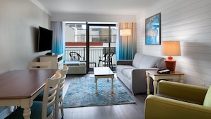 A hotel room with a dining area, a sofa, a TV, and a balcony with outdoor seating. - Partial OV King Suite - Beach Escape 7th Floor (Myrtle Beach)