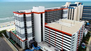 Un hotel de varios pisos con piscina en la azotea, junto a la playa.