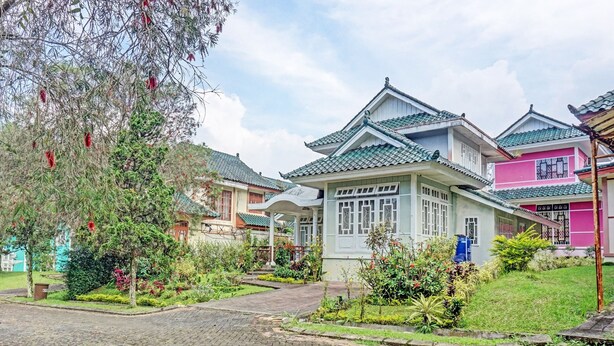 A traditional building with a tiled roof, surrounded by well-maintained gardens and a cobblestone pathway. - SPOT ON 91225 Kota Bunga Homestay Syariah (Cipanas)