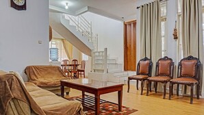 A living room with a sofa, chairs, a coffee table, and a staircase leading to another level. - SPOT ON 91225 Kota Bunga Homestay Syariah (Cipanas)