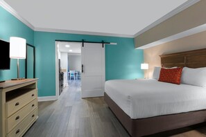 A hotel room with a bed, a TV, a desk, and a sliding door leading to a bathroom.