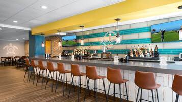 A bar area with a counter, bar stools, and a television screen displaying golf.