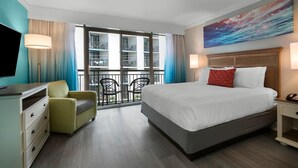 A hotel room with a large bed, a television, a desk, and a balcony with a view of the building's interior. - South Side View Two Room Suite  4th Floor (Myrtle Beach)