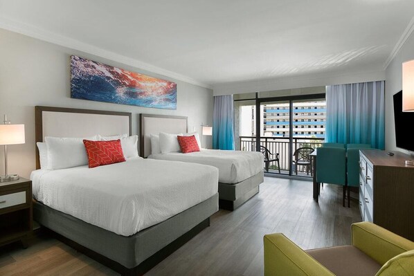 Une chambre d’hôtel avec deux lits, un bureau, une chaise, une télévision et un balcon donnant sur un immeuble.