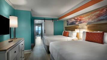 A hotel room with two beds, a TV, a desk, and a painting on the wall.