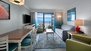 A hotel room with a balcony, a dining area, a sofa, a TV, and a lamp. - Majestic Oceanfront Suite 6th Floor (Myrtle Beach)
