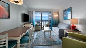 A hotel room with a balcony, a dining area, a sofa, a TV, and a lamp. - Relax in an Oceanfront Suite 7th Floor (Myrtle Beach)