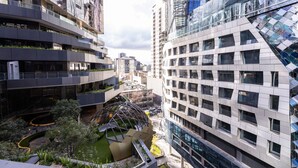 A modern urban building with multiple floors, large windows, and a central courtyard with a spherical structure. - The Ritz + Parking & Amenities (Melbourne)