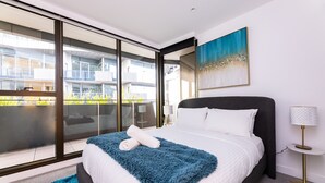 A modern hotel room with a large bed, a view of the city, and a balcony. - The Ritz + Parking & Amenities (Melbourne)