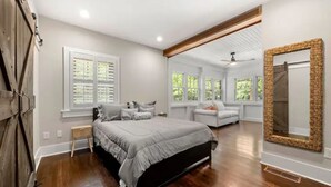 Un dormitorio con cama, mesita de noche, silla y un espejo grande.