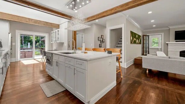 Una cocina amplia con una isla grande, vigas de madera y una lámpara moderna.
