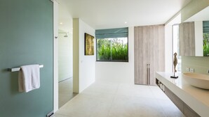 Un baño moderno con un ventanal grande, un lavamanos blanco y un perchero para toallas.