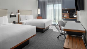 Une chambre d’hôtel avec deux lits, un bureau, une chaise, une télévision et un mini-bar.