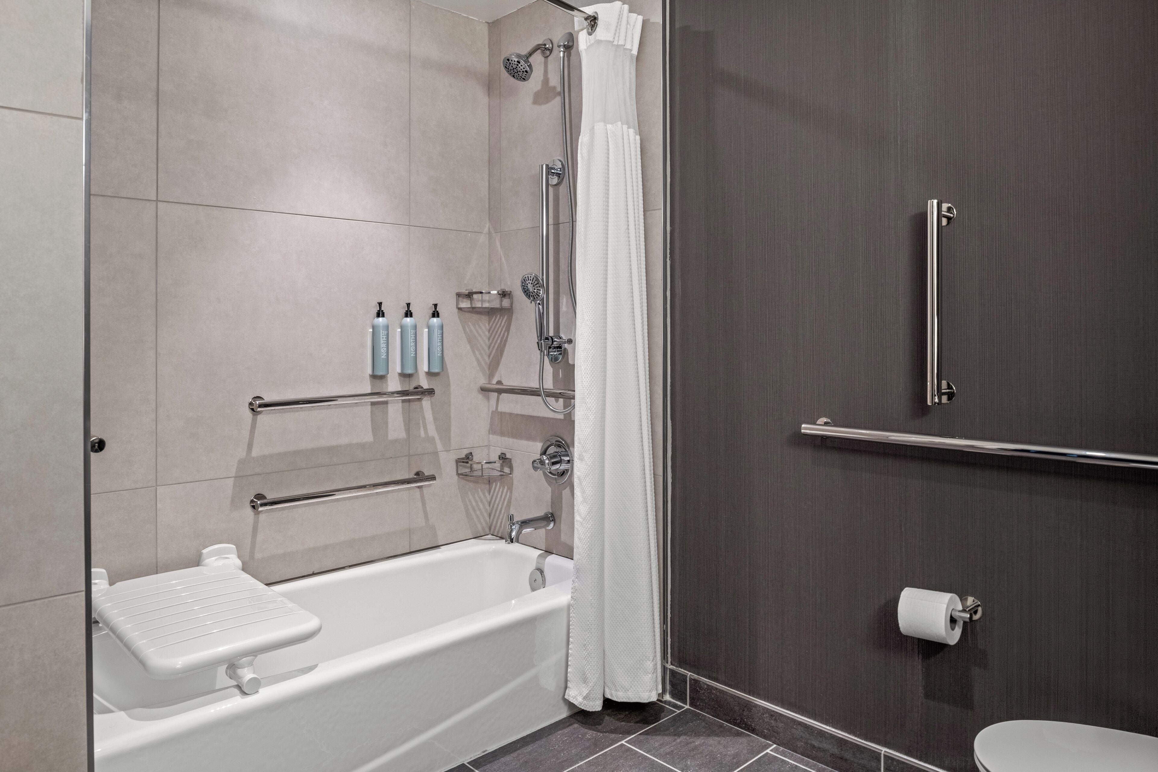 A modern bathroom with a bathtub, shower, and toilet.