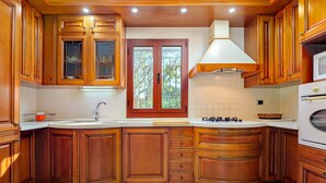 A kitchen with wooden cabinets, a white countertop, a window, and a microwave.