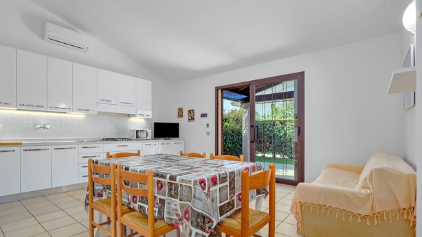 Eine moderne Küche mit weißen Schränken, einem Esstisch mit Stühlen und einer Couch.