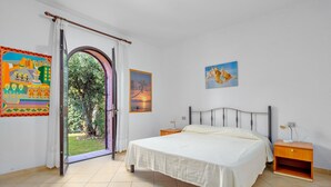 Ein Schlafzimmer mit Bett, Nachttischen, einem Fenster mit Vorhängen und Wandbildern.