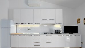 Eine moderne Küche mit weißen Schränken, einer Mikrowelle, einem Toaster und einem Flachbildfernseher.