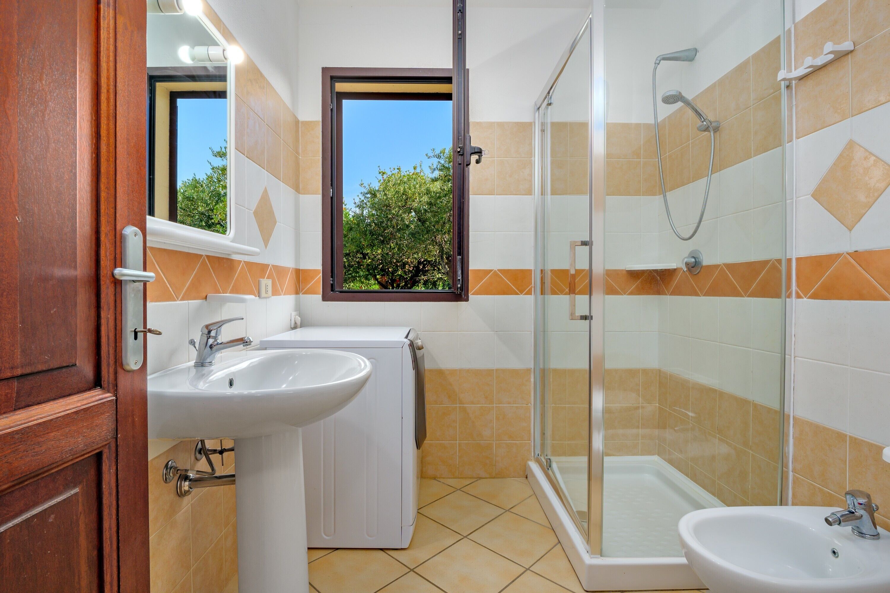 Baño con ducha, dos lavamanos, espejo y ventana.