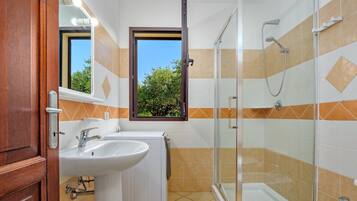 Baño con ducha, dos lavamanos, espejo y ventana.