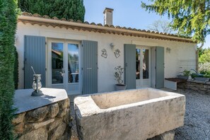 A stone building with a tiled roof, a stone well, and a potted plant. - Vacation Apartment "Agréable A La Campagne" with Private Pool, Private Terrace and Wi-Fi (Saint-Rémy-de-Provence)