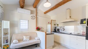 Una cucina moderna con mobili bianchi, forno integrato e soffitto in legno.