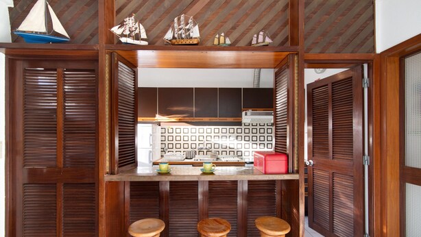 A kitchen with wooden cabinets, a countertop, and three stools.