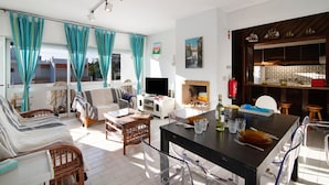 A living room with a sofa, chairs, a TV, a fireplace, and a dining area with a table and chairs.