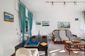 A dining area with a table, chairs, a laptop, and a sofa.