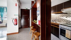 A kitchen with wooden stools, a stove, and a fire extinguisher.