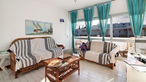 A living room with two wicker sofas, a coffee table with a laptop, and a painting on the wall.