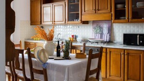 Une cuisine avec des meubles en bois, un plan de travail recouvert de carreaux blancs et une table à manger avec des chaises.