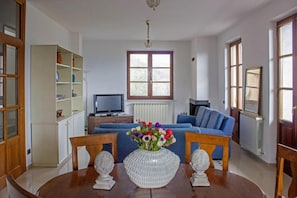 Ein Wohnzimmer mit Esstisch, blauem Sofa und einer Blumenvase.
