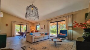 Amplia sala de estar con sofá, sillón, mesa de centro y lámpara colgante.
