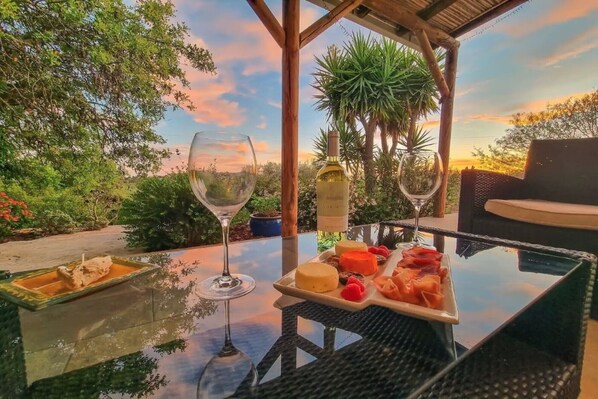Une table avec un verre de vin blanc, une bouteille de vin blanc et une assiette de fromages et de fruits variés.