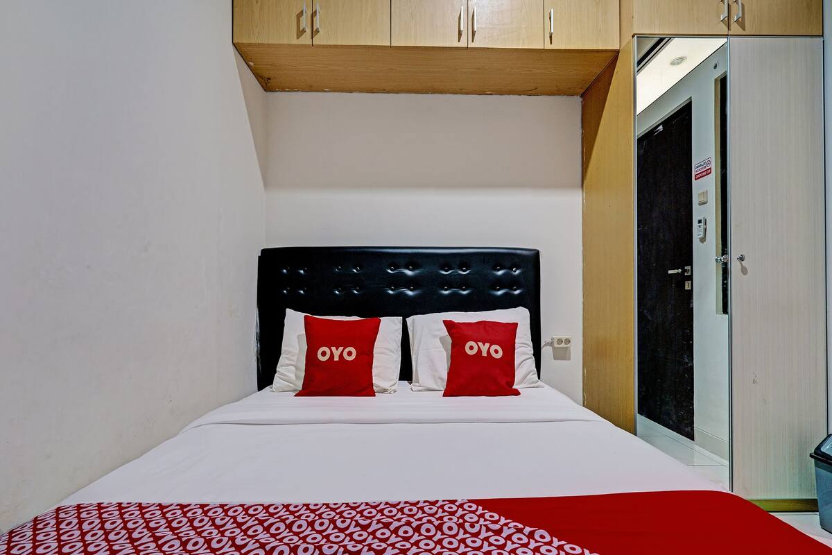 Una cama con una colcha estampada, dos almohadas con la palabra "OYO" y un cabecero de madera.