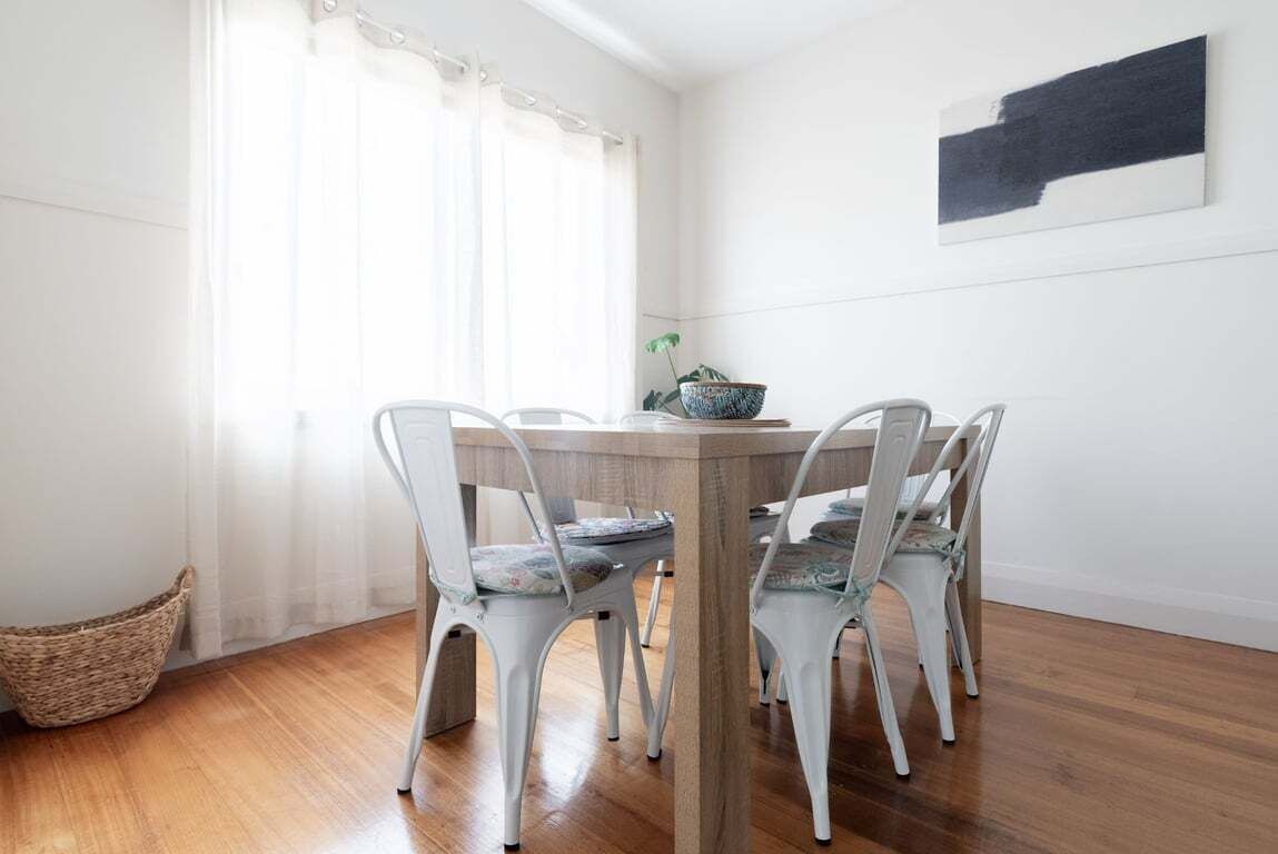 A dining area with a round table and white chairs, a woven basket, and a potted plant.
