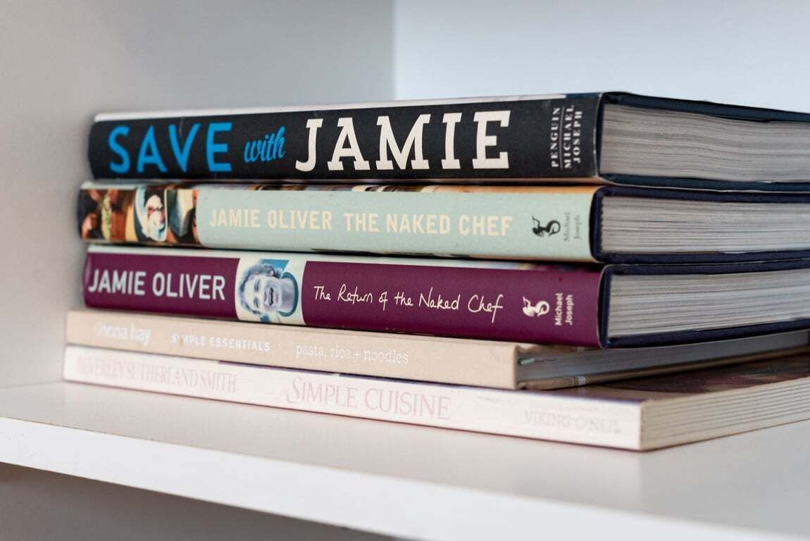A stack of books on a white shelf.