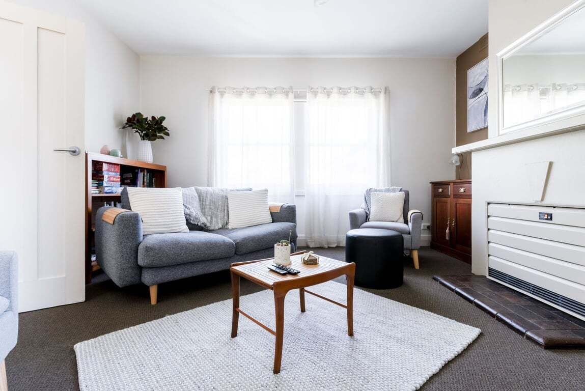 A living room with a sofa, armchair, coffee table, and a bookshelf.