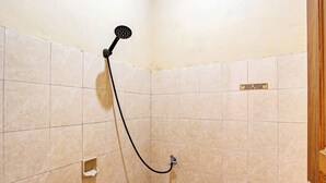 A shower with a handheld showerhead, a wall-mounted faucet, and a small shelf. - Hotel O 4 Saudara Hotel (Ambarawa)
